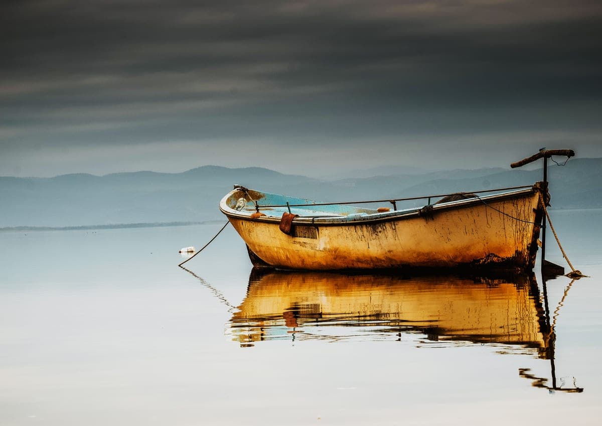 A small fishing boat on calm water on a cloudy morning