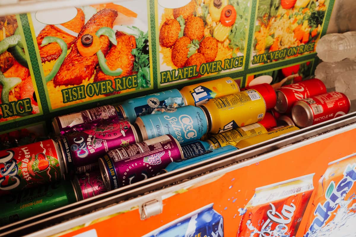 Illustrative stock photo: canned drinks packed in ice inside an open cooler at a street food stand