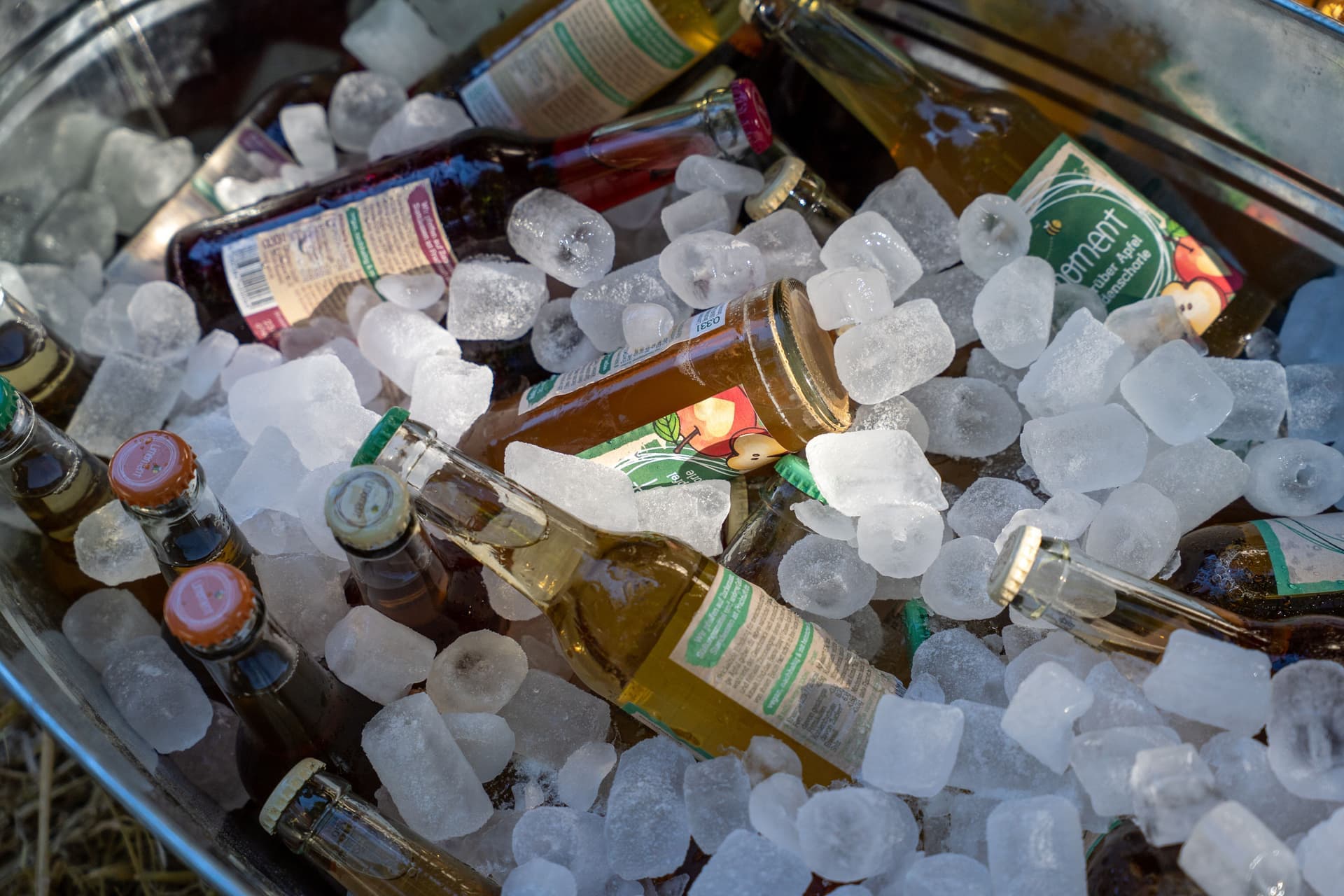 Glass bottles chilled in loose ice inside a metal tub outdoors