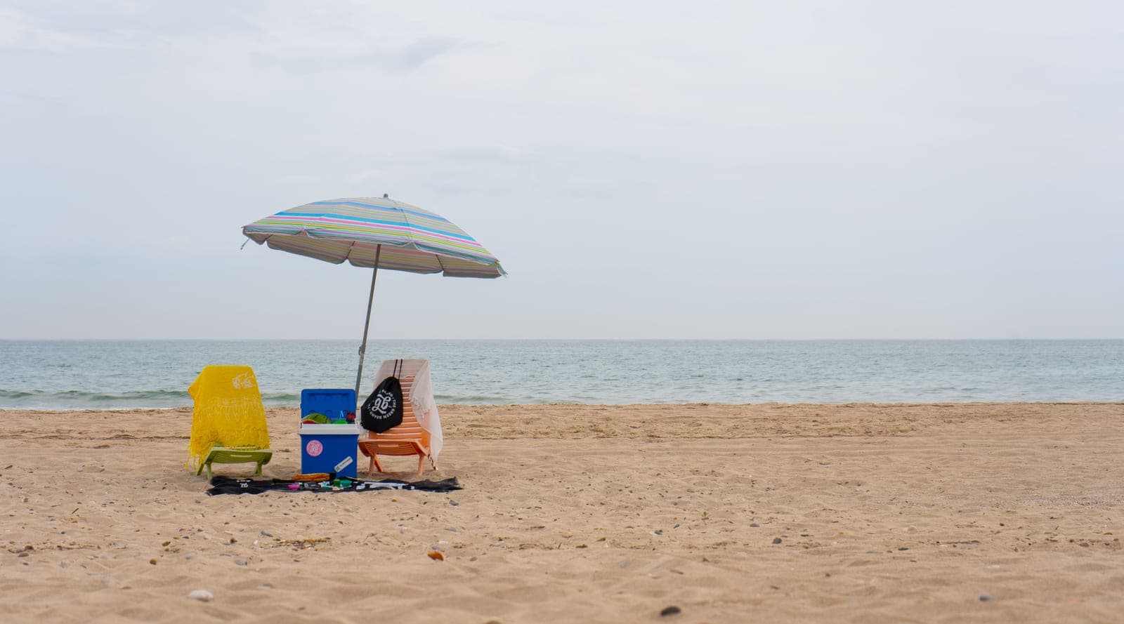Beach chairs and an umbrella set up on the sand by the sea